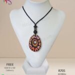 Egg shaped red clay pendant with colourful patterns and engravings on it.
