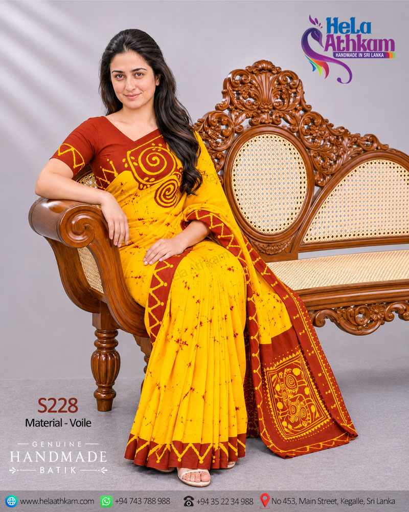 Sri Lankan handmade batic saree from Hela Athkam a woman proudly wearing this beautiful two color saree and sitting on a couch.